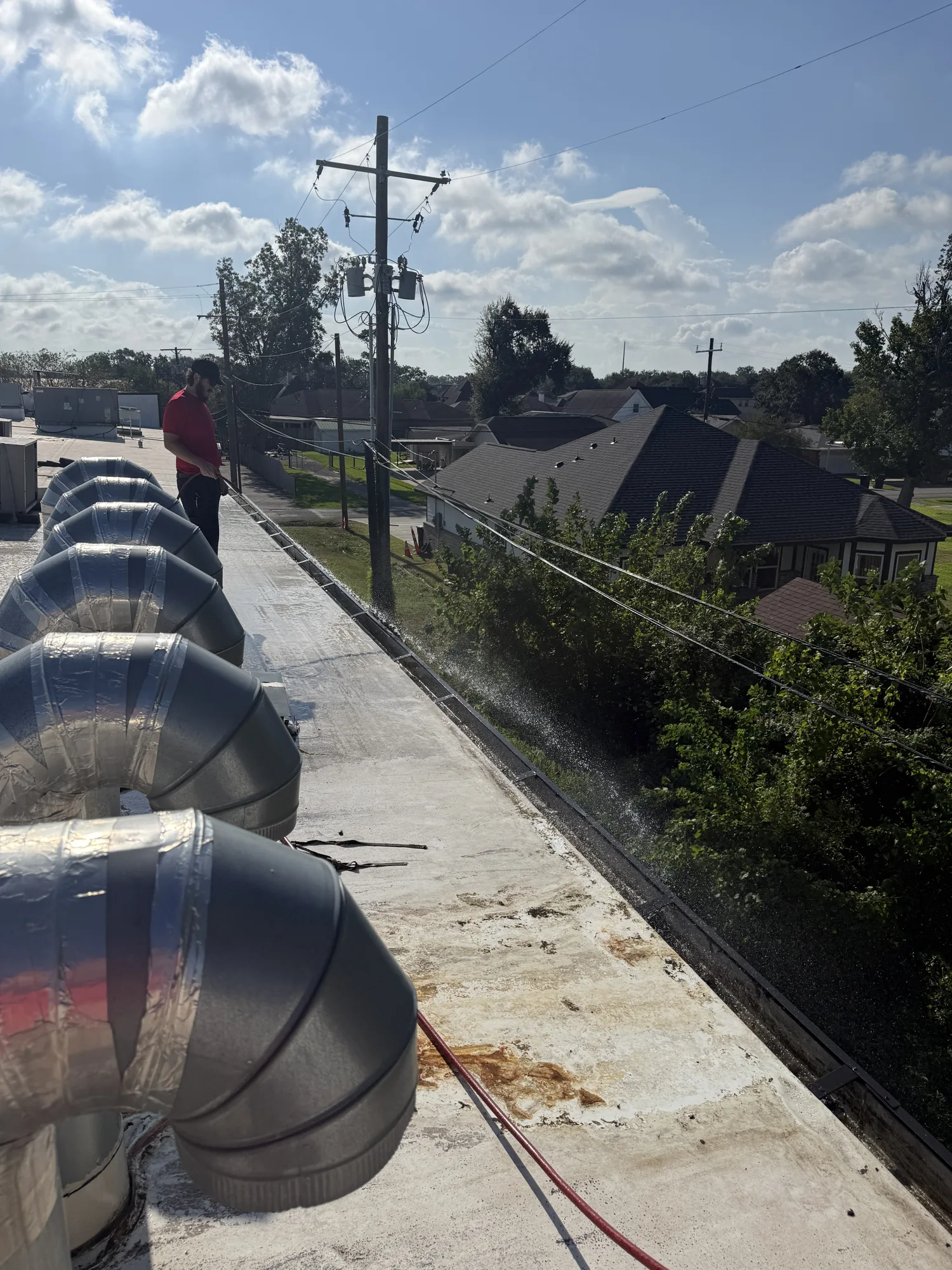 Clearing clogged gutters with a hydro jetter on a gas station roof in Nederland, TX