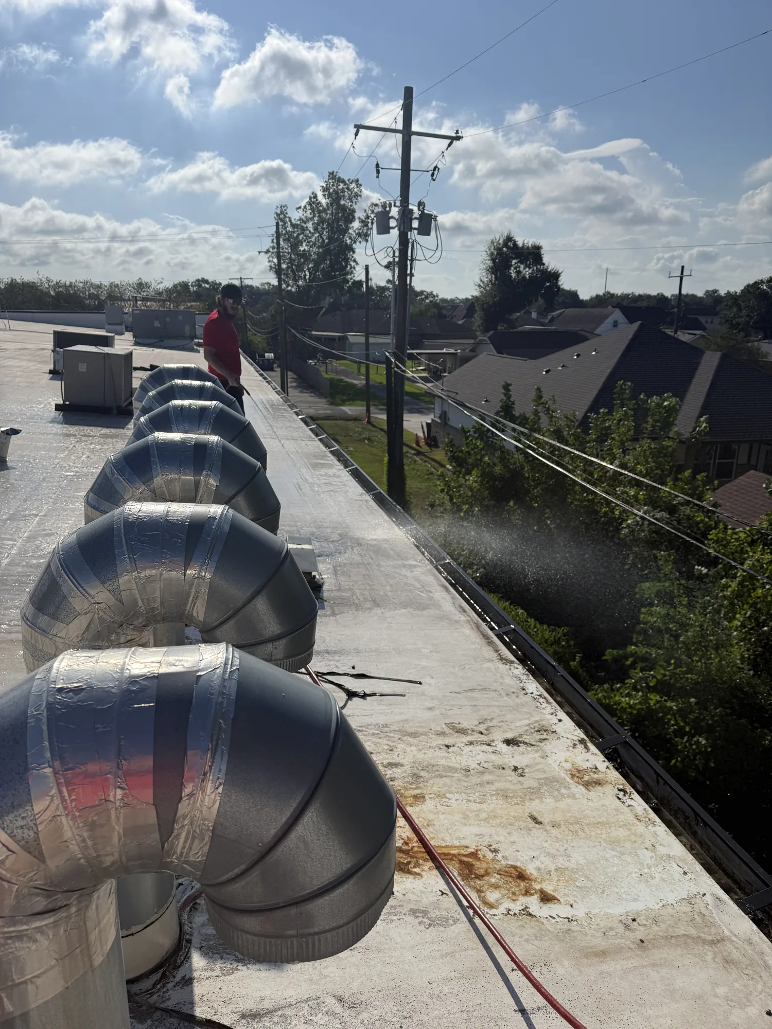Jetting debris out of a gas station's roof gutters in Nederland, TX