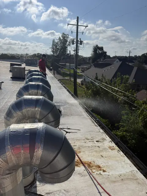 Jetting debris out of a gas station's roof gutters in Nederland, TX