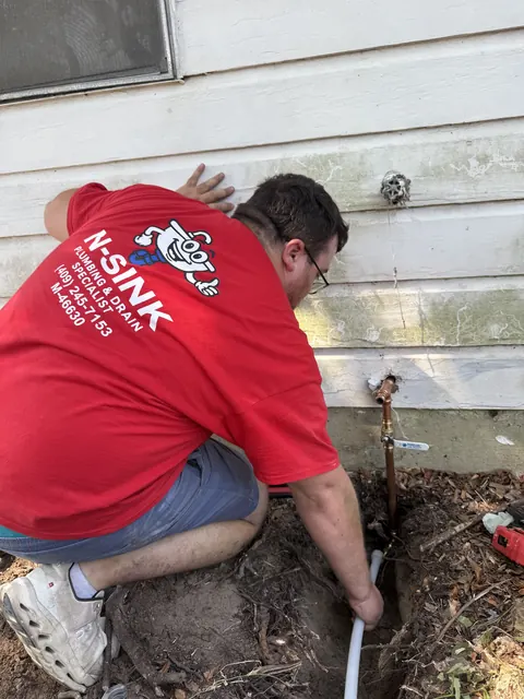 N-Sink repairing an outdoor water line at a home's hose bib